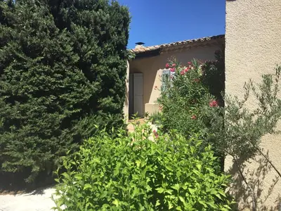 a building with a door and some bushes and trees at Petit cocon dans le Luberon in Lauris