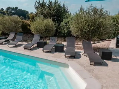 a row of lounge chairs next to a swimming pool at Le Petit Rossignol in Apt
