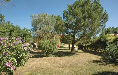 a garden with trees and flowers in front of a building at 2 Bedroom Cozy Home In Saint Trinit in Sault-de-Vaucluse