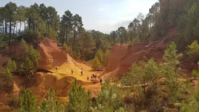 a group of people walking on a dirt path through a canyon at nid2nuit Nuance d'Ocres in Apt