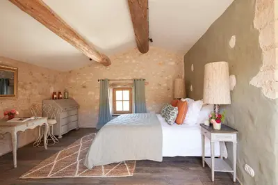 a bedroom with a bed and a table and a window at Le Mas Vermentino, La Bastide de Marie, Villa avec services in Ménerbes