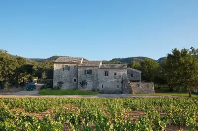 an old stone building with a field in front of it at Le Mas Vermentino, La Bastide de Marie, Villa avec services in Ménerbes