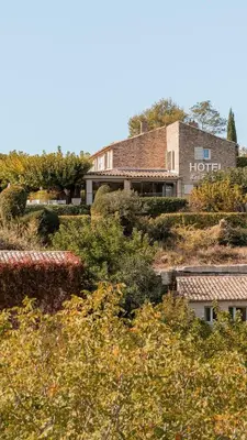 a building on top of a hill with trees at Mas des Romarins, The Originals Relais in Gordes