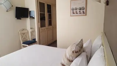 a bedroom with a white bed and a television at Le Mas Du Colombier in Cadenet