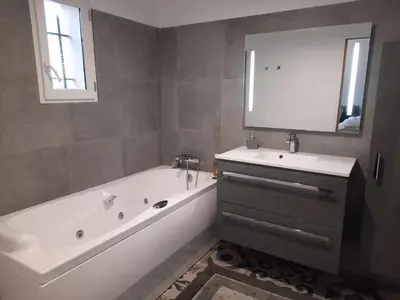 a bathroom with a white tub and a sink and a mirror at Villa Les Oliviers in Caromb