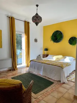 a bedroom with a large bed and a yellow wall at Mas de la Sacristière in Jonquerettes