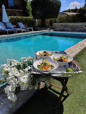 a table with plates of food next to a swimming pool at Hotel Bastide & SPA - Villa de Lourmarin in Lourmarin