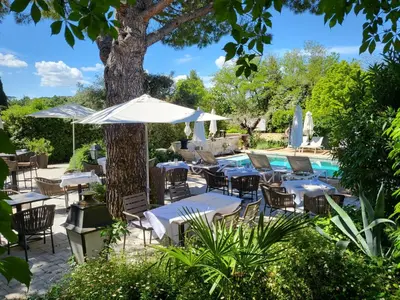an outdoor patio with tables and chairs and a pool at Hotel Bastide & SPA - Villa de Lourmarin in Lourmarin