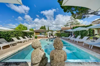 a villa with a pool with two statues in front of it at Hotel Bastide & SPA - Villa de Lourmarin in Lourmarin