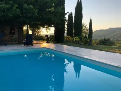 a blue swimming pool in front of a house at Villa du defens in Saint-Martin-de-Castillon