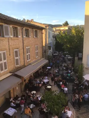 a crowd of people sitting at tables in a street at AJOUCADOU le perchoir in Lourmarin