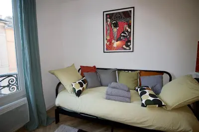 a couch with pillows on it in a room with a window at Le Petit Marius in Aix-en-Provence