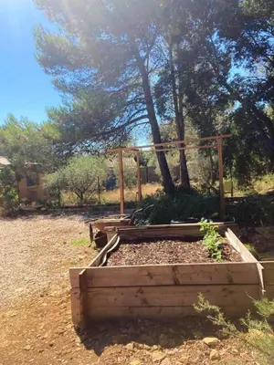 a wooden garden with a tree in the background at Charmant chalet à Cornillon-Confoux avec piscine partagée in Cornillon-Confoux