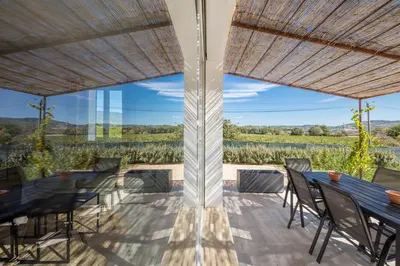 an outdoor dining area with a table and chairs and a large window at Villa Piscine Chauffée & climatisation, 5min du village in Saint-Saturnin-les-Apt