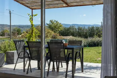 a table and chairs on a patio with a view at Villa Piscine Chauffée & climatisation, 5min du village in Saint-Saturnin-les-Apt