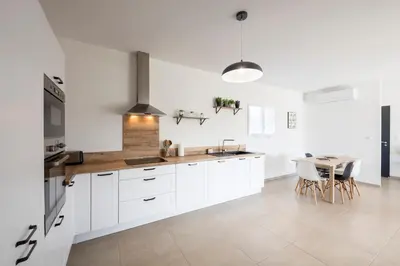 a white kitchen with white cabinets and a table at Villa Piscine Chauffée & climatisation, 5min du village in Saint-Saturnin-les-Apt