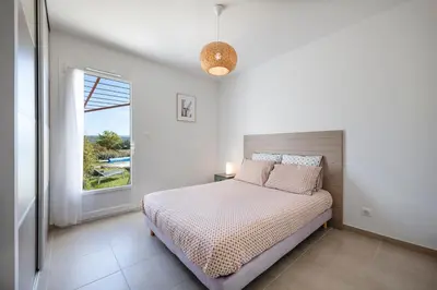 a white bedroom with a bed and a window at Villa Piscine Chauffée & climatisation, 5min du village in Saint-Saturnin-les-Apt