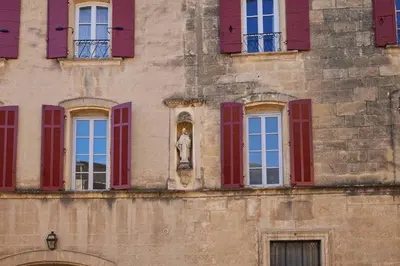 a building with red windows and a statue on it at Le Clos des Merveilles in Rognes