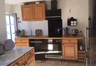a kitchen with wooden cabinets and a black stove top oven at Gîte Coquelicots in Montsalier