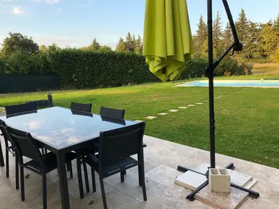 a table with chairs and an umbrella on a patio at Villa avec vue campagne in Carpentras