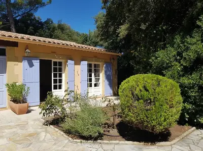 a small house with white doors and bushes at Maisonnette dans le Luberon - Bois Romay in La Bastide-des-Jourdans