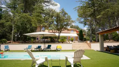 a pool with chairs and an umbrella next to a house at Maisonnette dans le Luberon - Bois Romay in La Bastide-des-Jourdans