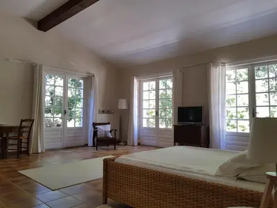 a bedroom with a bed and windows and a tv at Maisonnette dans le Luberon - Bois Romay in La Bastide-des-Jourdans