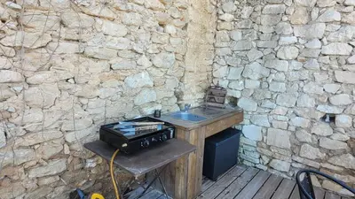 a kitchen with a sink and a stone wall at Entre blé et lavande in Bonnieux