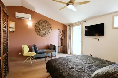 a bedroom with a bed and a chair and a tv at Le Jardin d'Érables St Remy 7 HA Piscine/Clim in Paluds de Noves