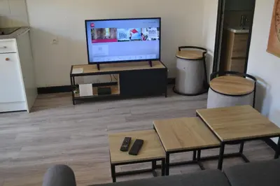 a living room with a flat screen tv on a stand at Appartement Proche Quai Rouget in LʼIsle-sur-la-Sorgue