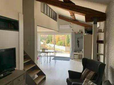 a living room with a television and a table with chairs at Clos du Cardinal in LʼIsle-sur-la-Sorgue