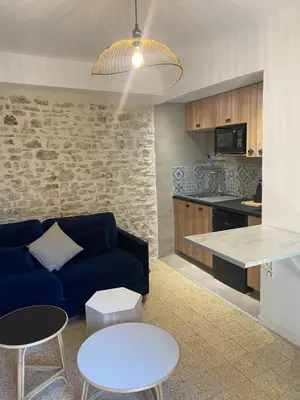 a living room with a blue couch and a kitchen at La tour 2: Appart neuf au cœur de la petite venise in LʼIsle-sur-la-Sorgue