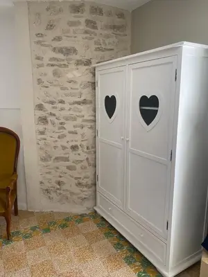 a white cabinet with hearts on it next to a wall at La tour 2: Appart neuf au cœur de la petite venise in LʼIsle-sur-la-Sorgue