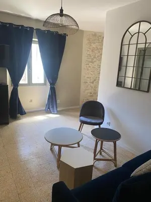 a living room with two tables and a chair at La tour 2: Appart neuf au cœur de la petite venise in LʼIsle-sur-la-Sorgue