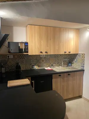 a kitchen with wooden cabinets and a black counter top at La tour 3: Appart au cœur de la petite Venise in LʼIsle-sur-la-Sorgue