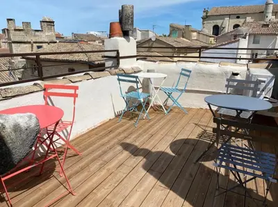 a deck with chairs and tables on a roof at La tour 3: Appart au cœur de la petite Venise in LʼIsle-sur-la-Sorgue