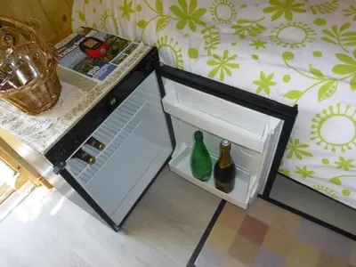 an open refrigerator with two glass bottles in it at CABANE perchée dans les arbres in Robion en Luberon