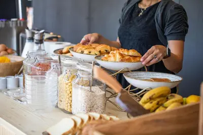 a woman standing in front of a table with bowls of food at thecamp hôtel - Aix en Provence in Aix-en-Provence