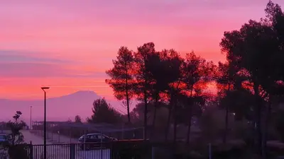 a sunset with trees and a mountain in the background at thecamp hôtel - Aix en Provence in Aix-en-Provence