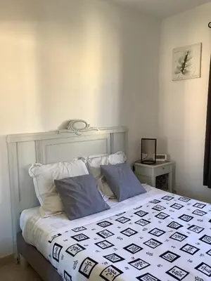 a white bed with two blue pillows in a bedroom at Les Oliviers in Mallemort