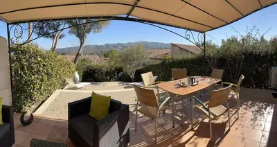 a patio with a table and chairs under an umbrella at Les Oliviers in Mallemort