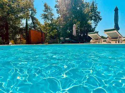 a swimming pool with two chairs and the water at les Bartavelles in Roussillon