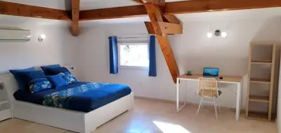 a bedroom with a bed and a desk with a laptop at Maison calme et rénovée 