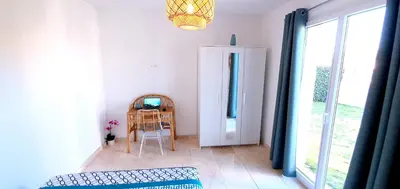 a room with a chair and a table with a television at Maison calme et rénovée 