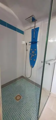 a bathroom with a shower with a blue seat at Maison calme et rénovée 