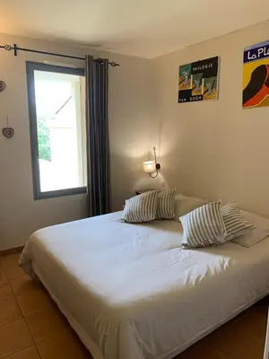a bedroom with a white bed with two pillows at appartement cosy avec climatisation réversible GOLF DE SAUMANE in Saumane-de-Vaucluse