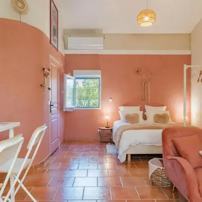 a bedroom with a bed and a chair and a window at Domaine Plan des Devens in Roussillon