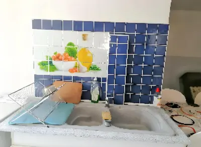 a kitchen with a sink with a blue tiled wall at Appartement charmant à Avignon - 50 m² - Terrasse privée in Avignon