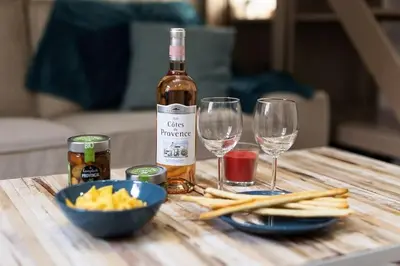a bottle of wine and two wine glasses on a wooden table at Exotic Stones Hyper Centre Fontaine Moussue in Salon-de-Provence