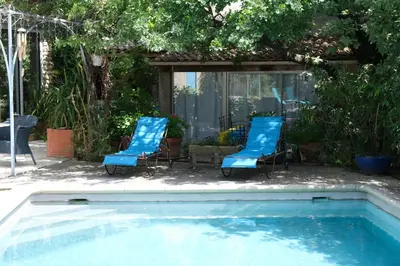 a bedroom with a bed with pink flowers on it at jolie location, maison avec piscine et joli jardin fleuri, à oppède dans le luberon en provence – 6 personnes in Oppède